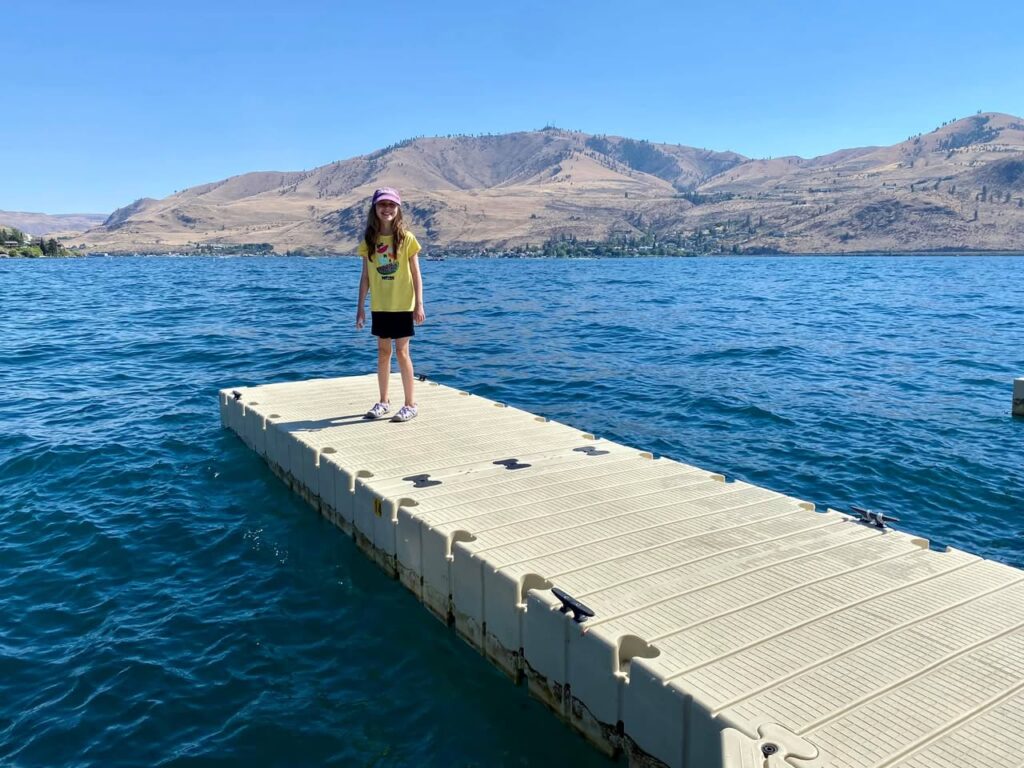 A person standing on a floating dock at Lake Eureka with dry mountains in the background.