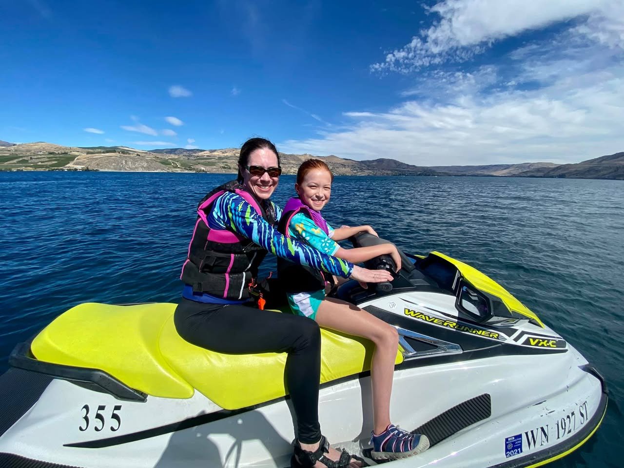 Lake Chelan Jet Ski Two people riding a jet ski on a lake under a clear blue sky. Detailed shots of the jet ski and surrounding water.
