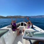 Two people are enjoying a boat ride on calm blue waters.