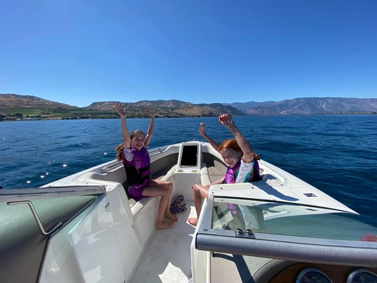 Lake Chelan Boating Two people are enjoying a boat ride on calm blue waters.