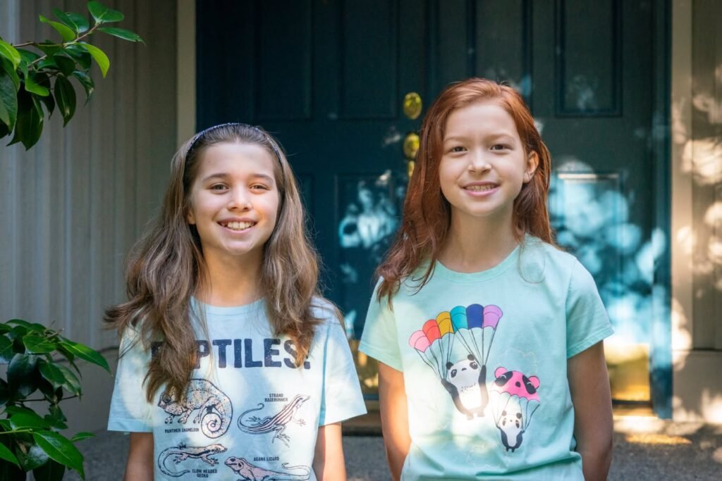Two young girls smiling in their summer outfits. A homey photo capturing personal travel or vacation moments.