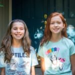 Two young girls smiling in their summer outfits. A homey photo capturing personal travel or vacation moments.