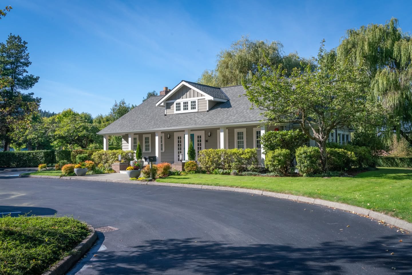 North Creek Clubhouse A view of a well-maintained house with a curved asphalt driveway under a clear blue sky.