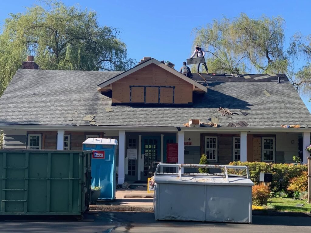 A collage of photos showing workers on a residential roof with a new dormer addition. Construction materials and a dumpster are visible on the lawn of a Pacific Northwest home.