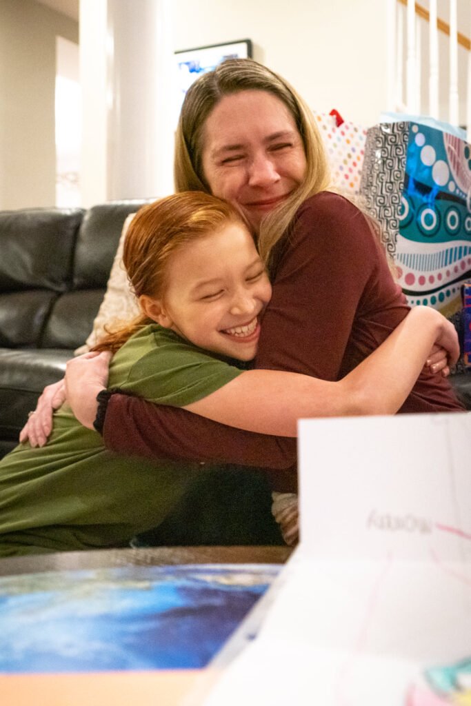 Two individuals sharing a heartfelt hug in a cozy living room, conveying warmth and familial connection.