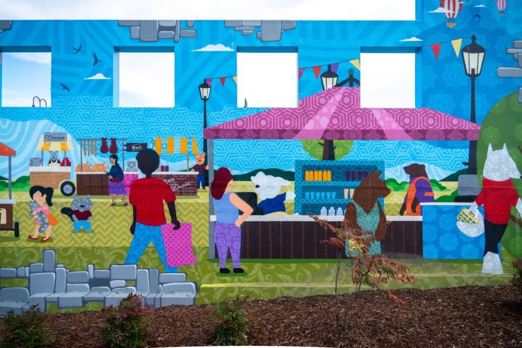 A vibrant mural depicting a bustling community market scene with diverse people and colorful stalls.