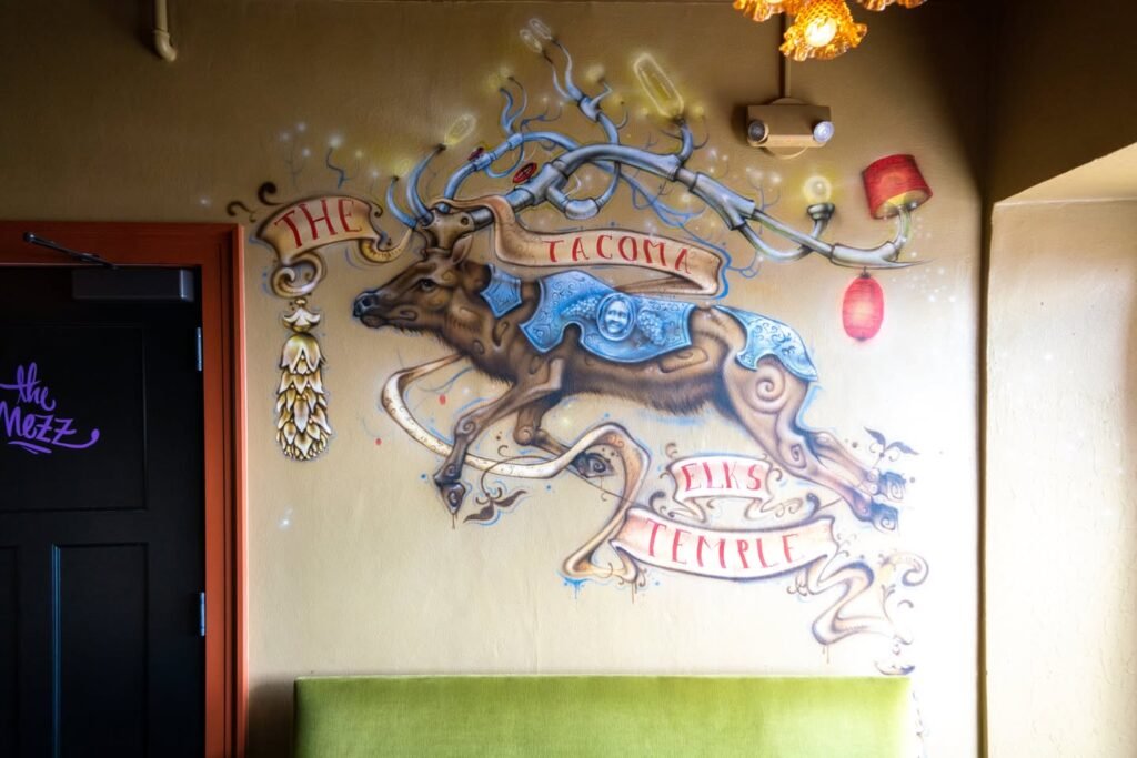 Hand-painted mural featuring the Le Cola mascot from Pokemon with whimsical banners and decorative elements on a cafe wall.