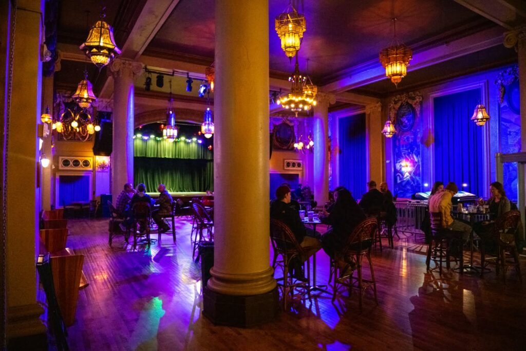 A collage of images showing an evening scene in a bar with purple lighting and chandeliers. Patrons are seated at the bar enjoying the atmosphere.