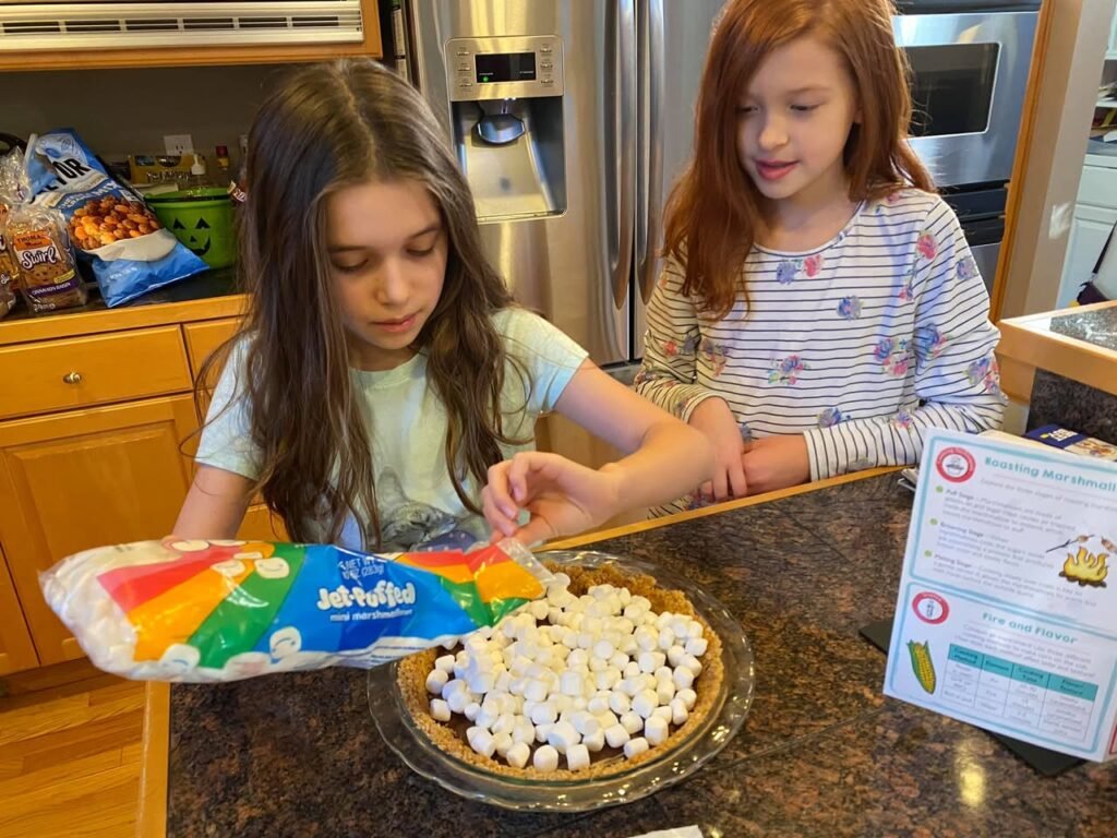 Kids preparing a s'mores pie in a home kitchen