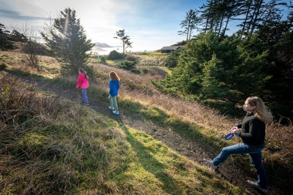 A family hiking through a grassy, wooded hillside in the Pacific Northwest.
