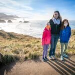Bye Disco, Hello Mando A family poses on a grassy cliff overlooking the Pacific Ocean. The distant rocky outcrops are partially shrouded in morning mist.