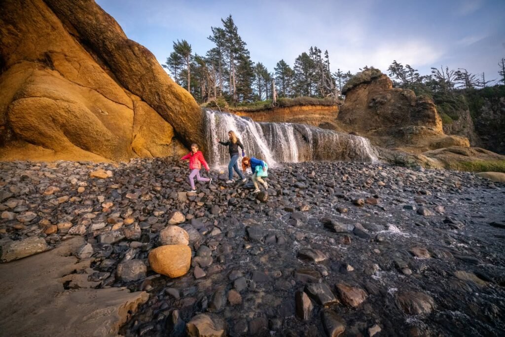 A family enjoying a hike at a scenic waterfall with mossy granite rocks in the Pacific Northwest.