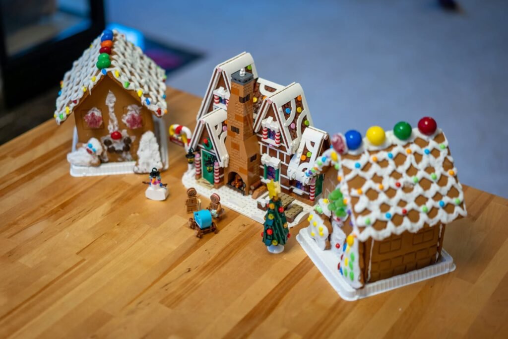 A detailed view of multiple handmade gingerbread houses decorated with candies, icing, and gumdrops on a wooden table.