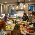 First D&D Adventure A group of people gathered around a large kitchen island enjoying a meal together in a modern kitchen.