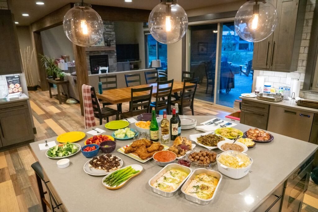 A spread of diverse foods displayed on a kitchen counter with various colorful dishes.