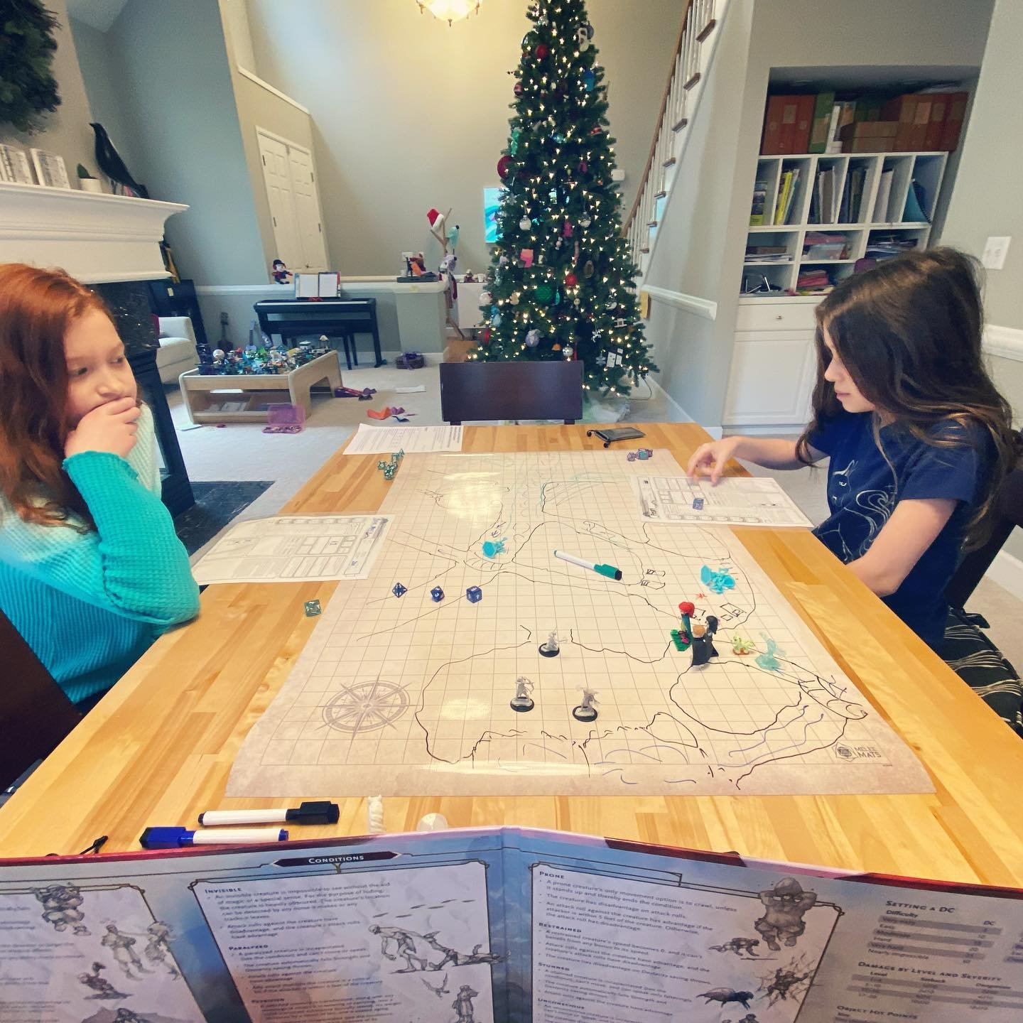 First D&D Adventure Children playing a board game at a table with a decorated Christmas tree in the background. A cozy holiday scene in a modern home.