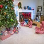 First D&D Adventure A cozy living room decorated for the holidays with a large tree, gifts, red stockings on the fireplace, and individuals in matching pajamas gathering around the tree.