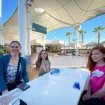 Cathedral Rock People enjoying a sunny day at an outdoor plaza with palm trees and modern architecture.
