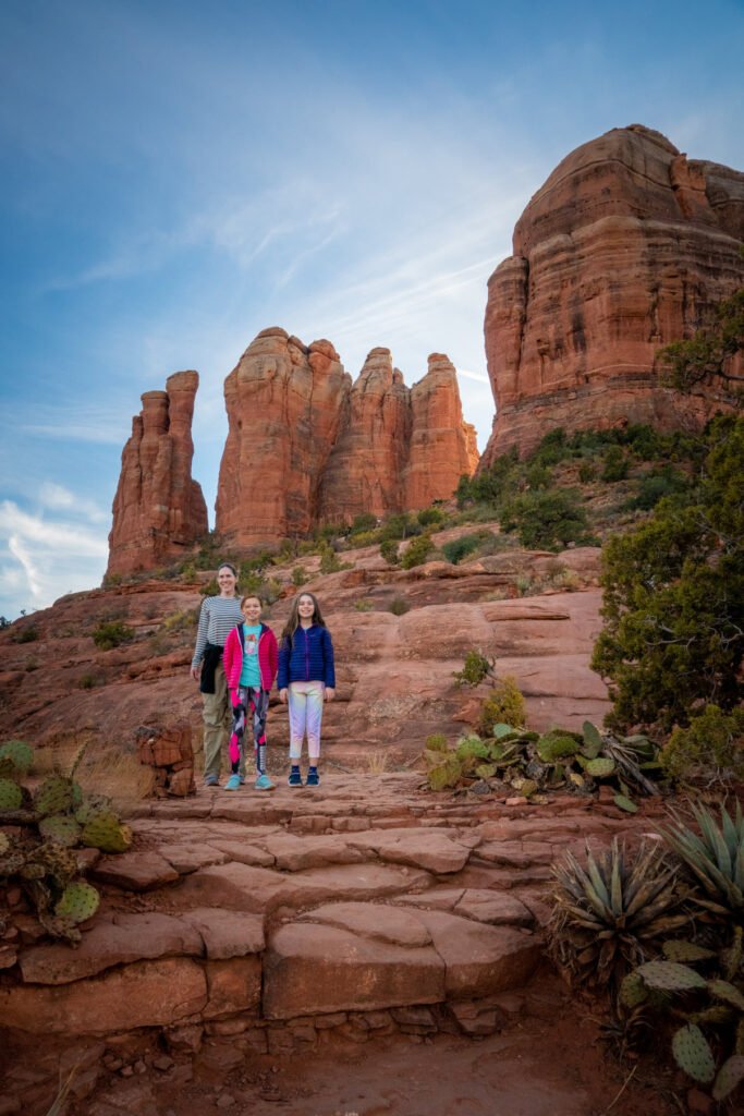 A family admires towering red sandstone formations along a rocky trail.