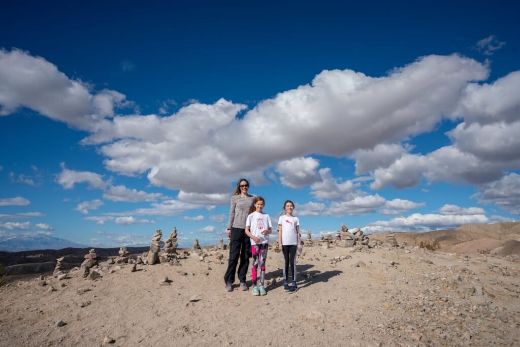 Family group posing among small rock formations beneath a bright blue, partly cloudy sky.