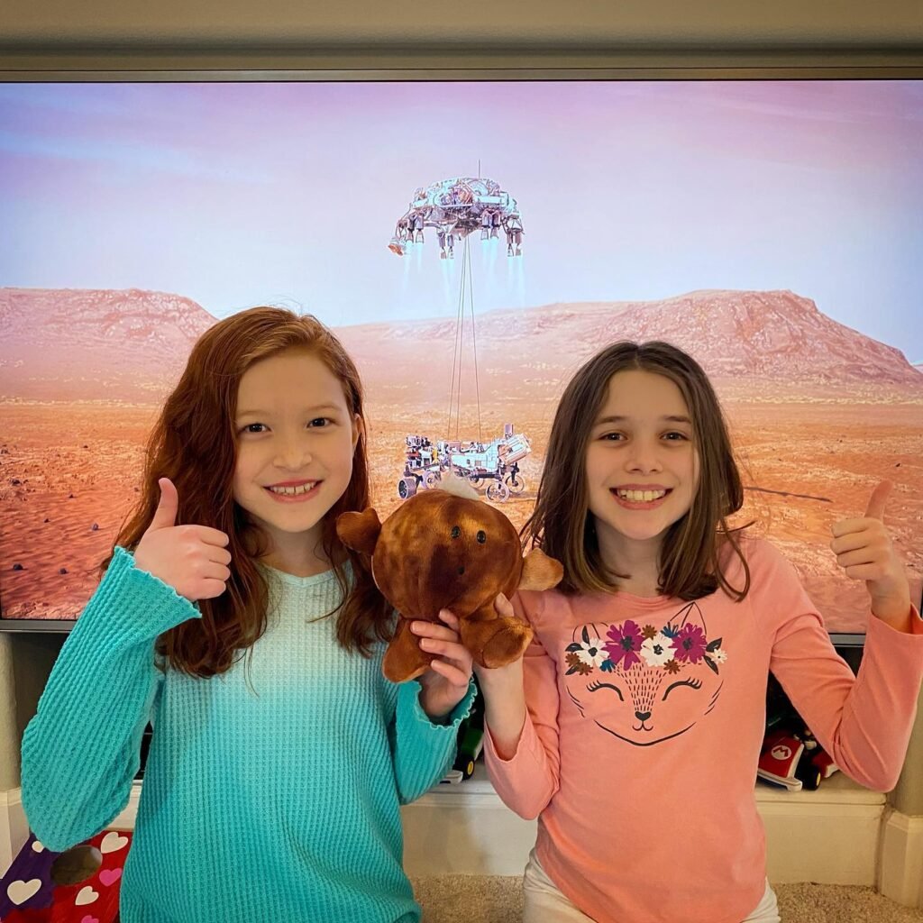 Two children giving a thumbs up while watching a science fiction movie with a desert planet.