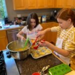 Perseverance Two children bake cookies in a home kitchen with wooden cabin.