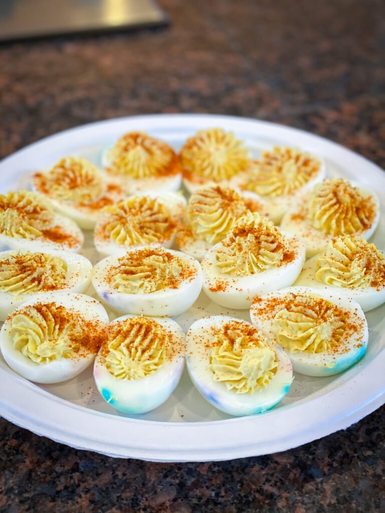 Hard-boiled egg halves topped with a pipette design, dusted with paprika on a white plate.
