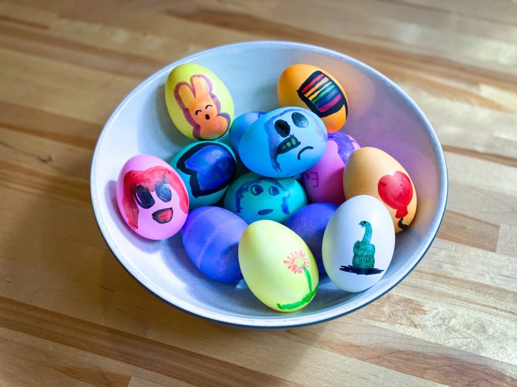 A collection of hand-painted colorful Easter eggs with cartoon faces in a white bowl.