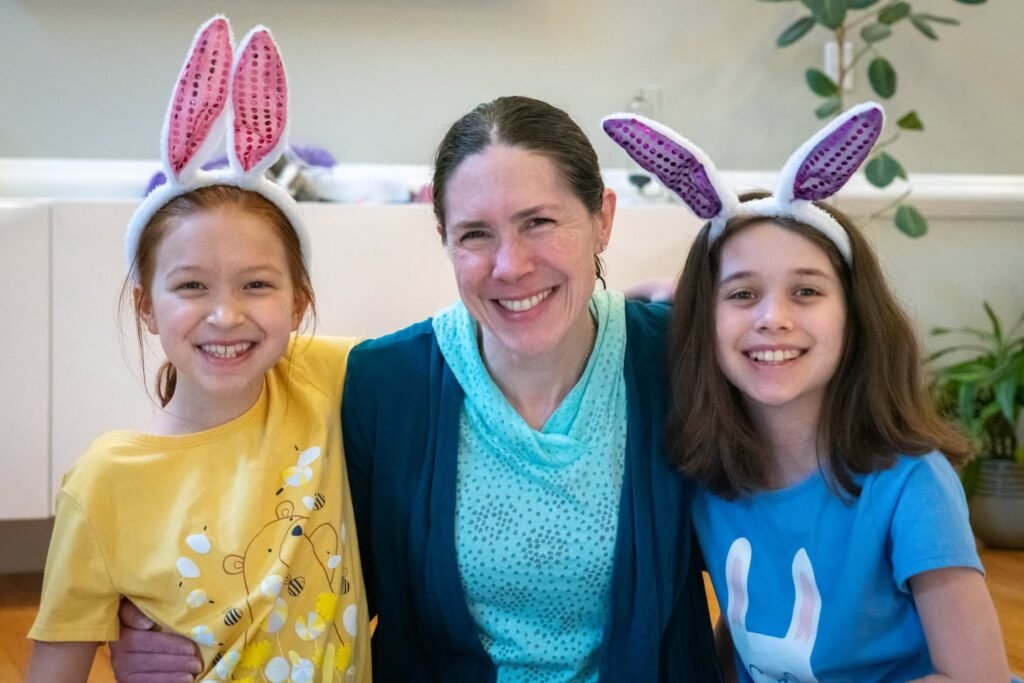 A family wearing colorful Easter bunny ears smiles together indoors.