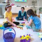 Children and an adult collecting dyed Easter eggs in a cozy living room with a purple basket and colorful eggs on the floor.