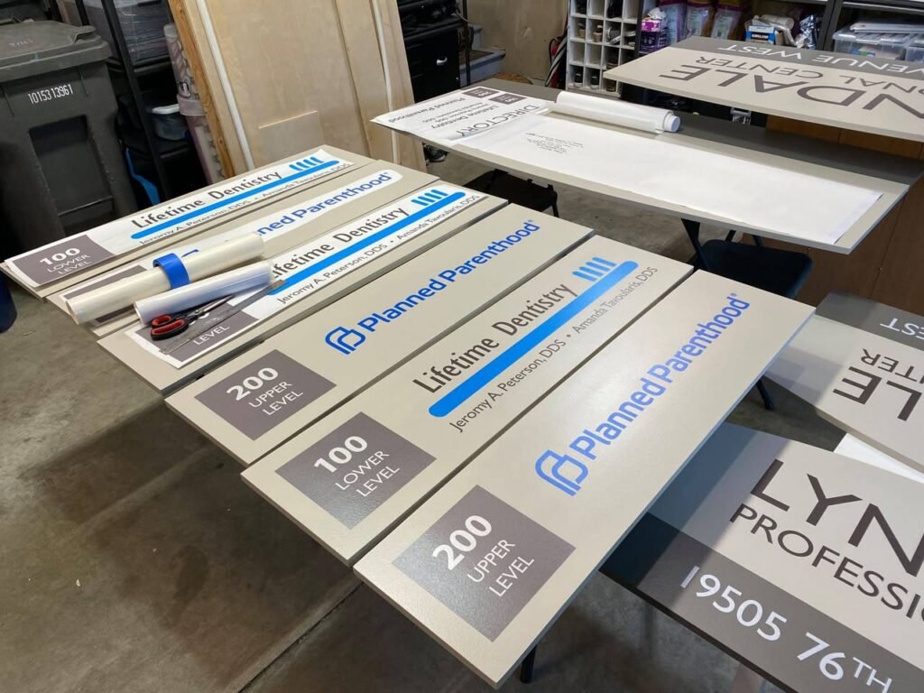 An indoor space is filled with new Planned Parenthood signs and banners, including large 200-Lane Level and 19505 76th Street signs.