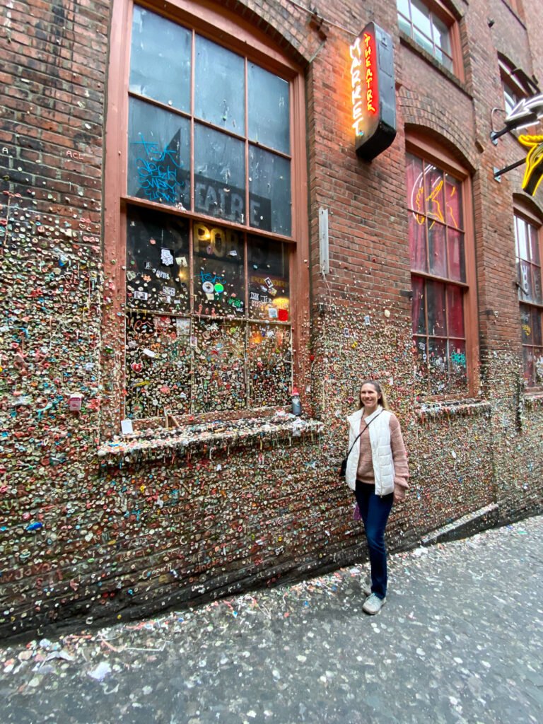 A person stands in front of the colorful brick wall at the Gumball Museum in Pittsburgh.