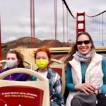 A family wearing masks on a ferry with the Golden Gate Bridge in the background. A scenic view of the iconic suspension bridge in San Francisco.
