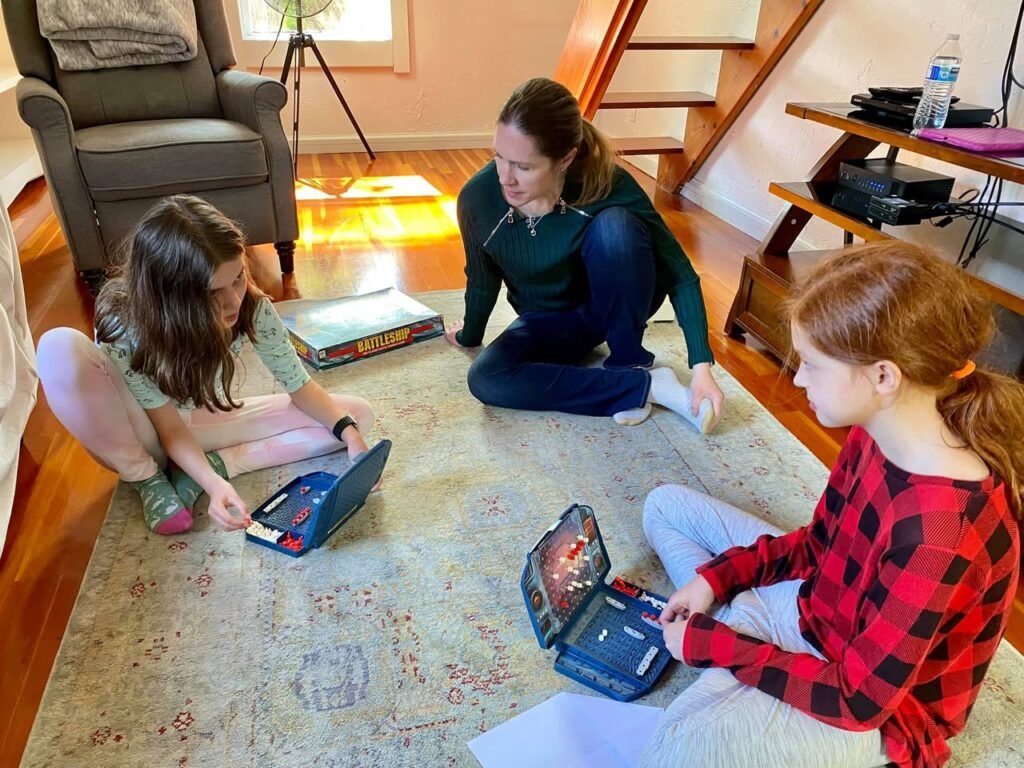 People sitting on a living room rug playing small tabletop games with electronic bases.