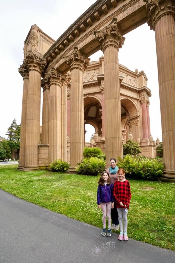 Family members posing in front of the Palace of Fine Arts with its iconic arches.