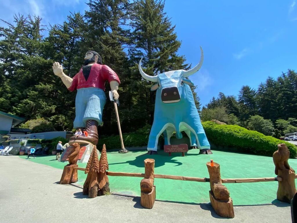 A large wooden sculpture of a moose and a lumberjack figure at a nature-themed attraction in the Pacific Northwest.