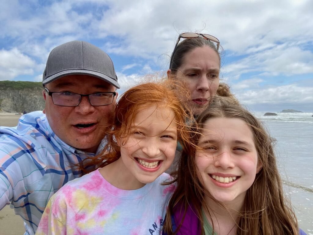A family of four taking a selfie on a sunny beach.
