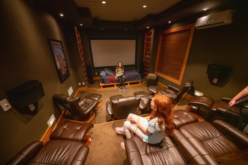 A cozy home theater with plush leather recliners and a large projection screen. The room features full surround sound with speakers around the room.