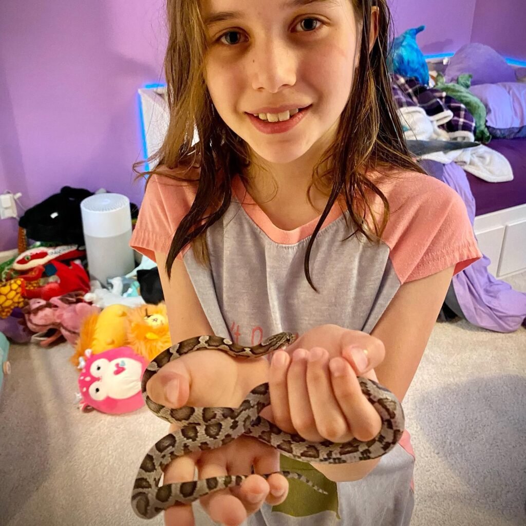 A person holding a small snake in their hands.