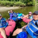 Icicle Gorge A family enjoying a relaxing river floating trip in colorful inflatable tubes, surrounded by lush greenery. A self-portrait captures the group in safe life jackets on calm waters.
