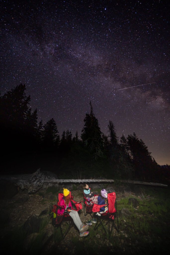 Travelers gaze up at the Milky Way from a campsite near a lake. Highlights of a Pacific Northwest camping trip under the stars.