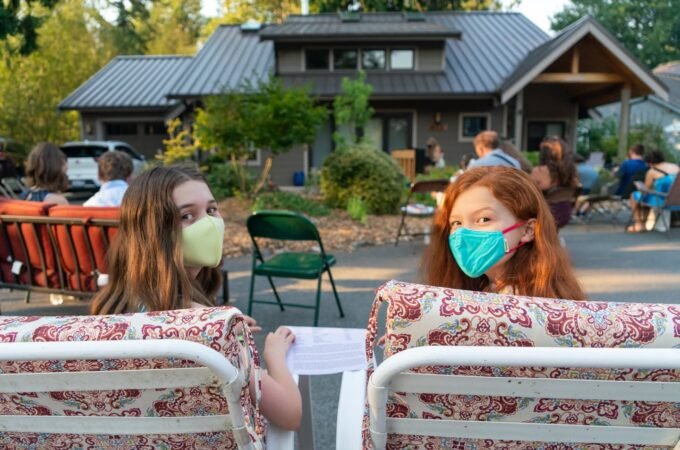 Peaked at an outdoor social gathering with a rustic cabin in the background and guests seated in the foreground