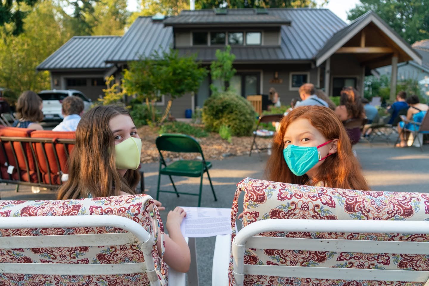 Summer Recital Peaked at an outdoor social gathering with a rustic cabin in the background and guests seated in the foreground