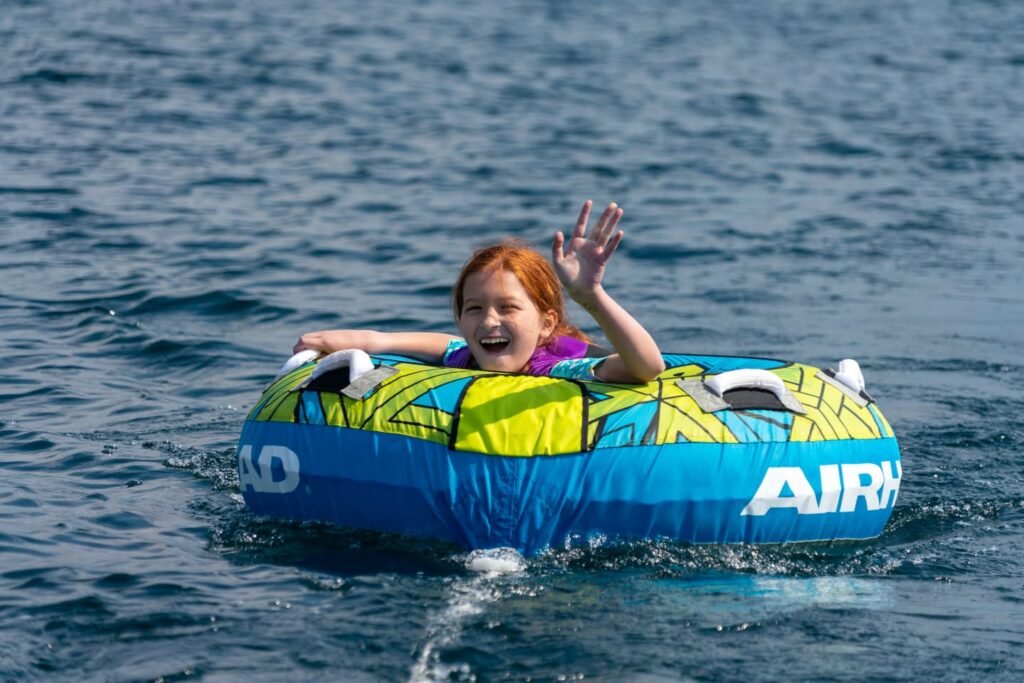 A person enjoys a day on the lake in a colorful inflatable tube. The water sparkles under the sunlight.