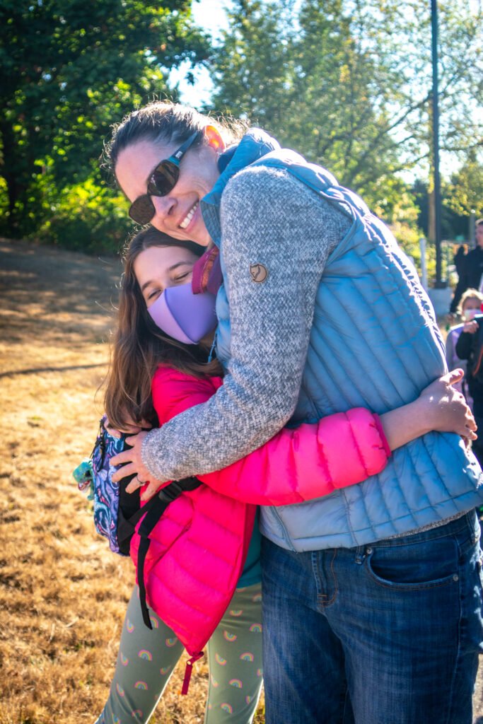A person giving a teenager a warm hug on a sunny day.