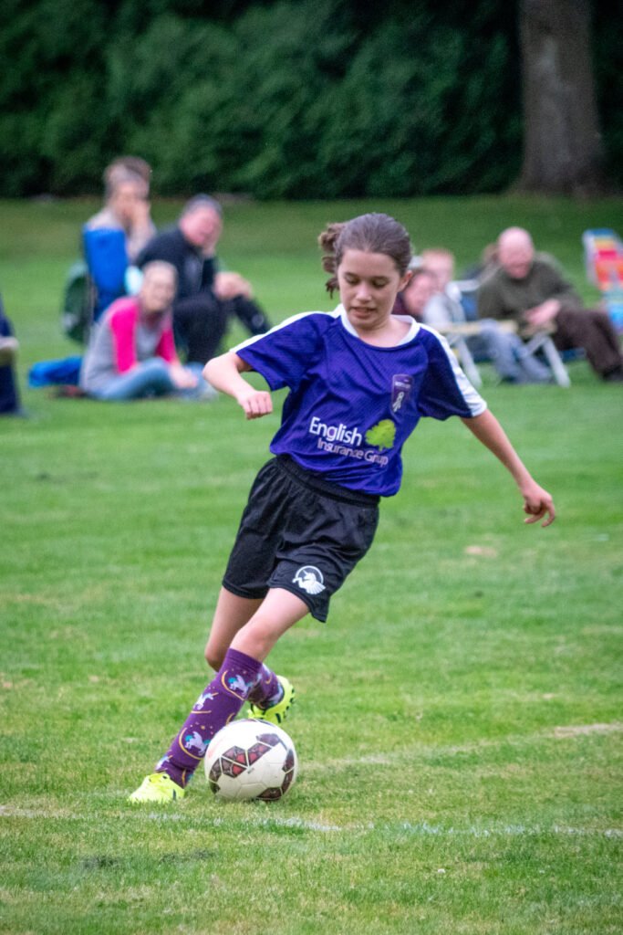 A young soccer player kicks the ball on a grassy field.