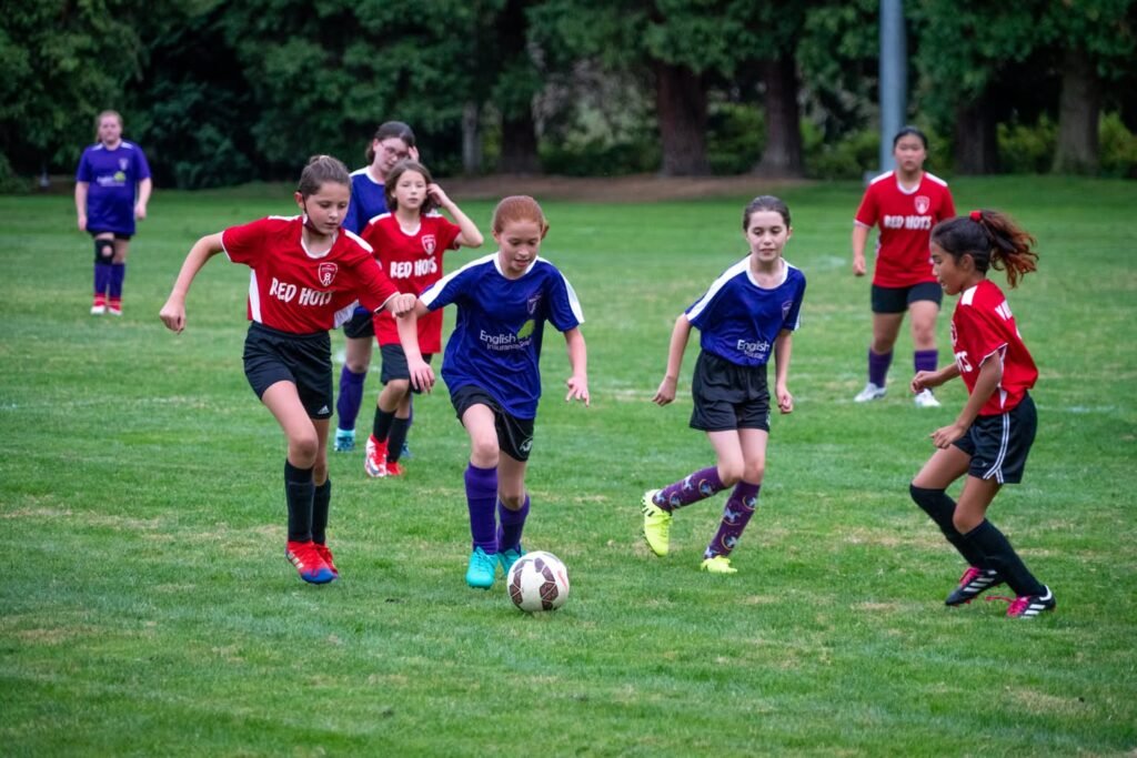 Young soccer players in red and blue uniforms competing on grass. A close-up captures movement on the field with a soccer ball.