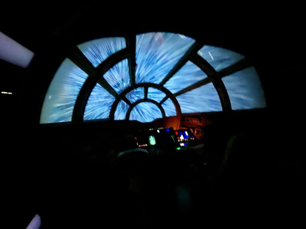 A large glass mosaic depicts a dramatic night sky, lighting a museum display.