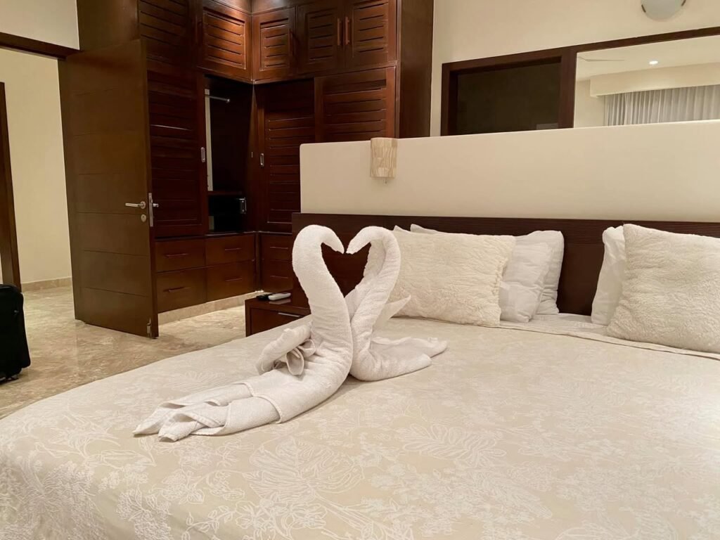 A hotel bed with towels folded into the shape of swans, showcasing a cozy and elegant room setting.