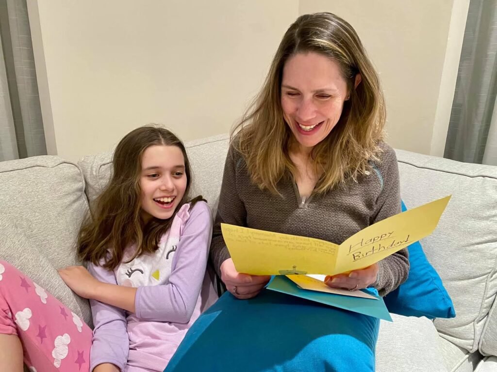 A woman and child reading from a yellow book together on a couch, enjoying a cozy moment at home.